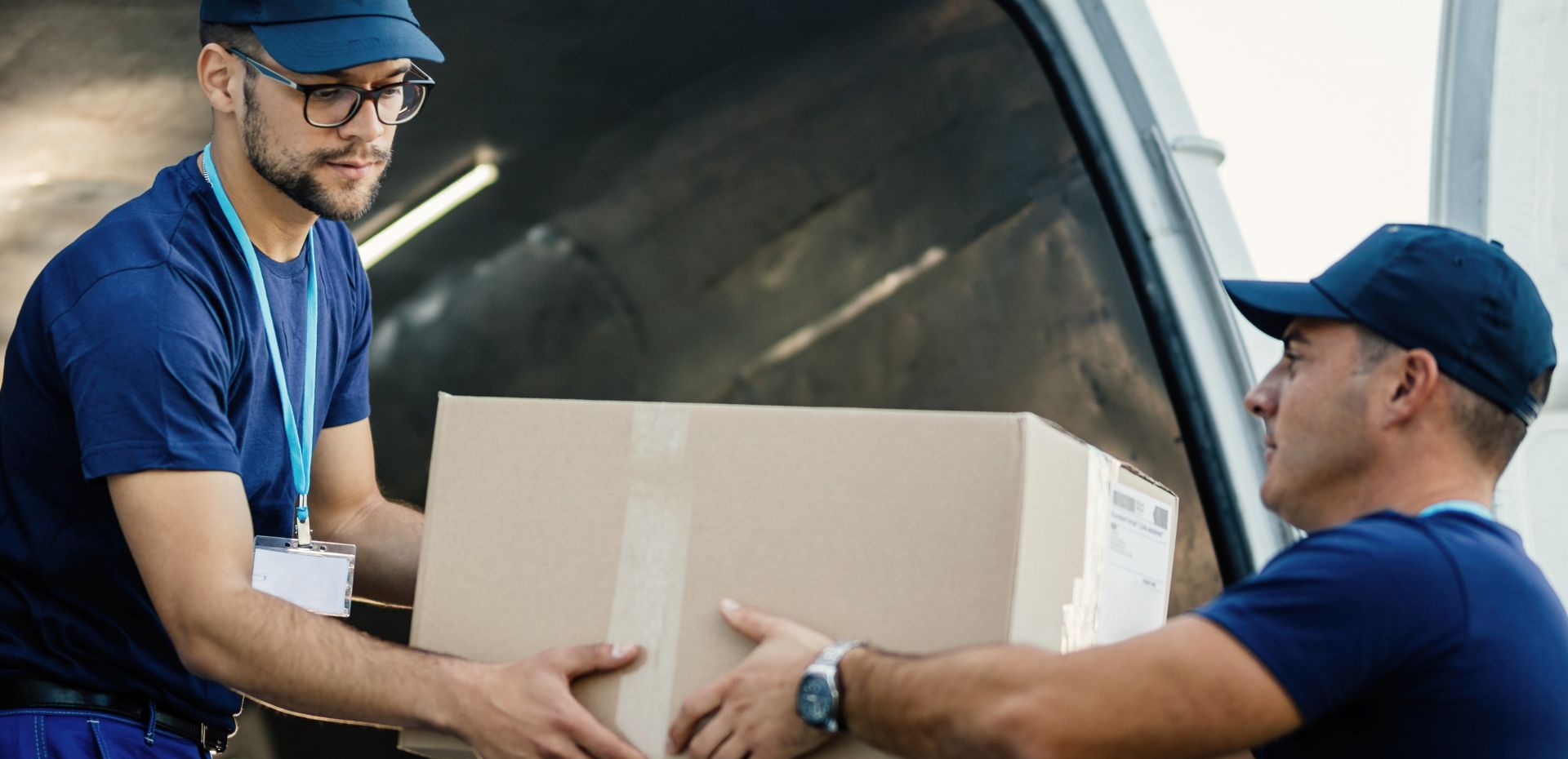 Two couriers load boxes into a van for shipment, showcasing logistics and teamwork.
